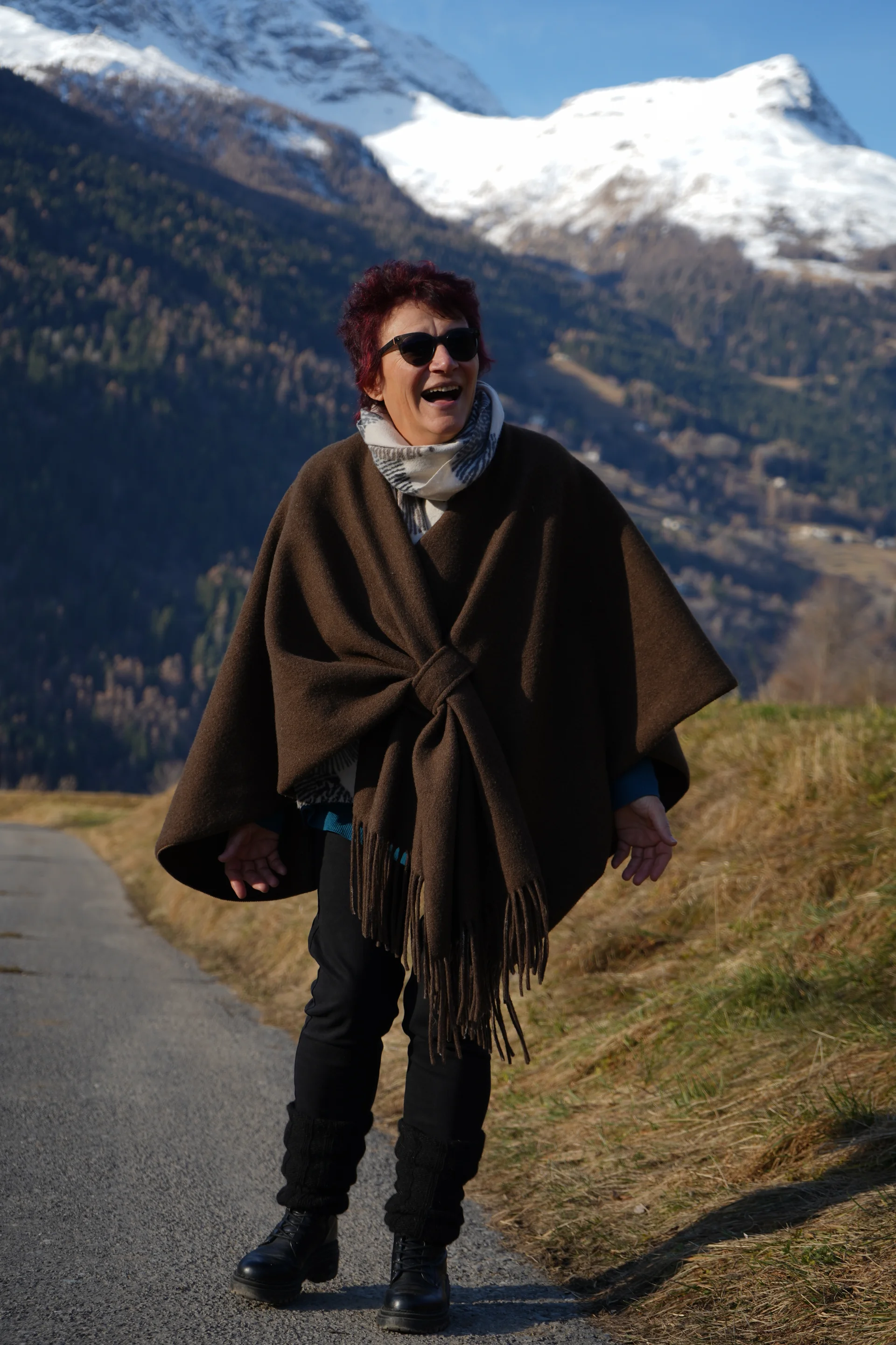 Figura in poncho sulla strada di montagna